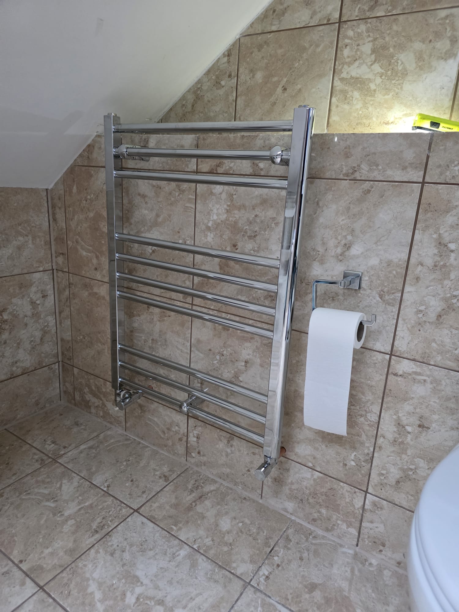 Chrome ladder heated towel rail installed in a tiled loft bathroom, Surrey
