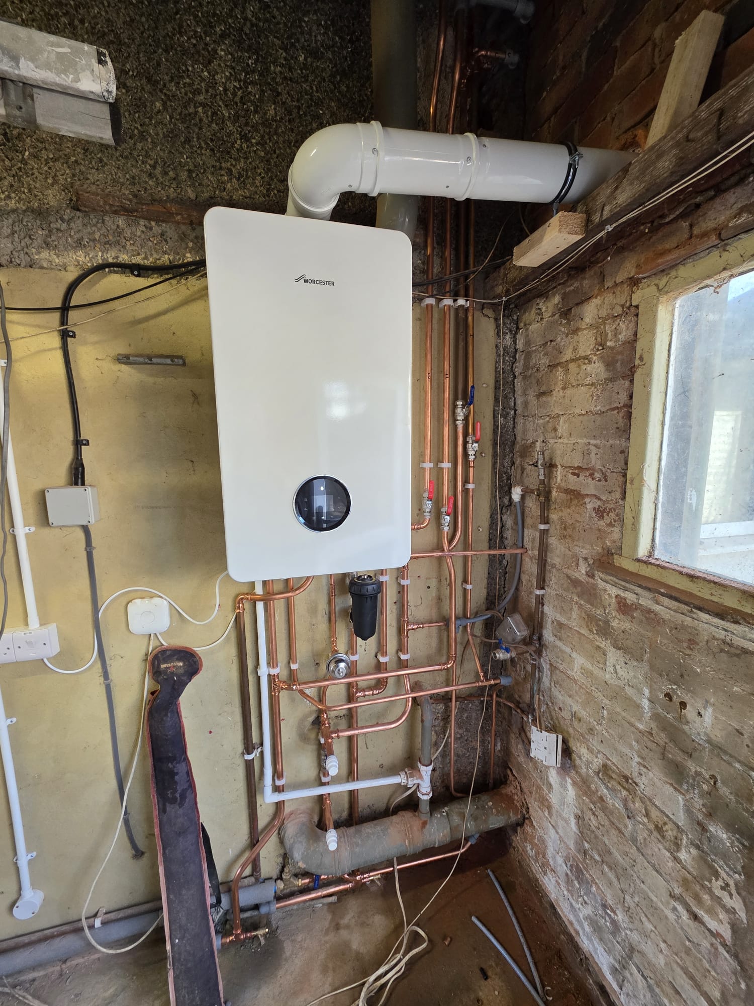 Worcester Bosch combi boiler installed in an outbuilding with exposed brickwork and full copper pipework rebuild, Surrey
