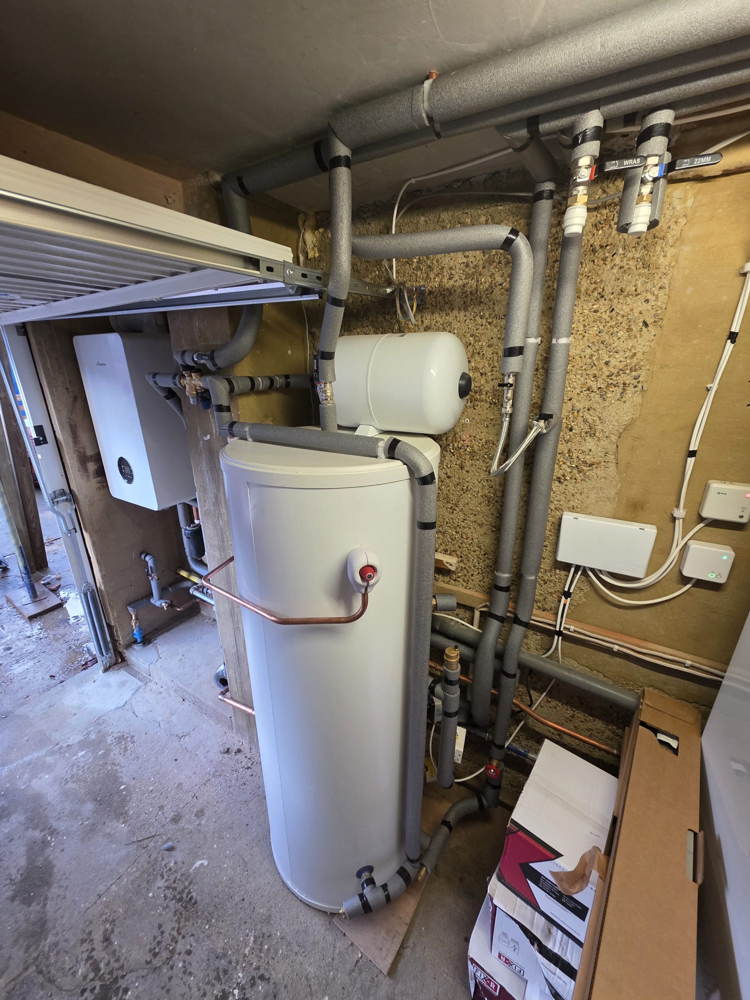 System boiler paired with unvented cylinder and fully lagged pipework in a Surrey garage plant room